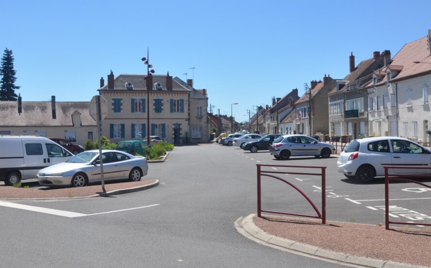 Parking place Saint-Nicolas avec des véhicules stationnés sous le soleil