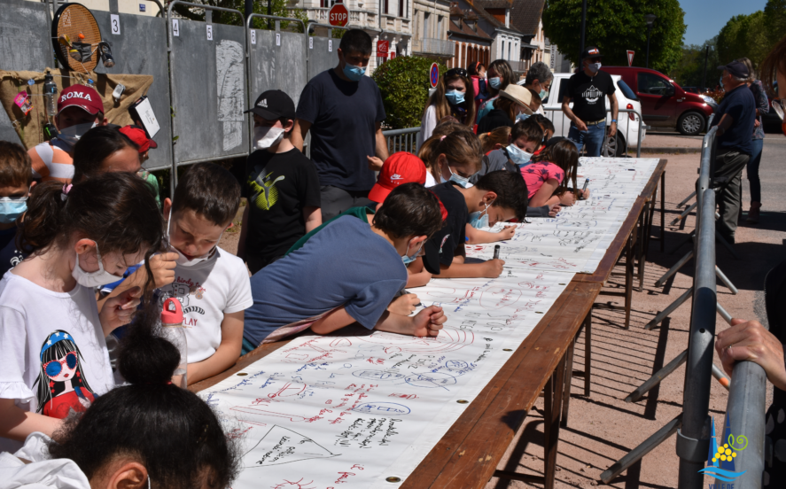 Les enfants élaborent une banderole avec des dessins pour sensibiliser la population à la pollution en ville