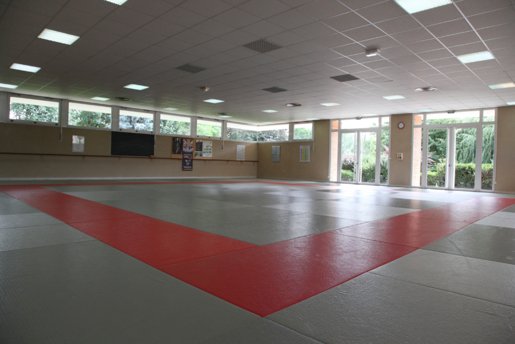 Salle d'arts martiaux avec ses tatamis reflétant la lueur du jour