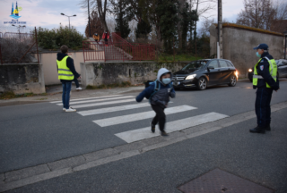 Enfant qui traverse pour aller à l'école sous la protection d'un agent
